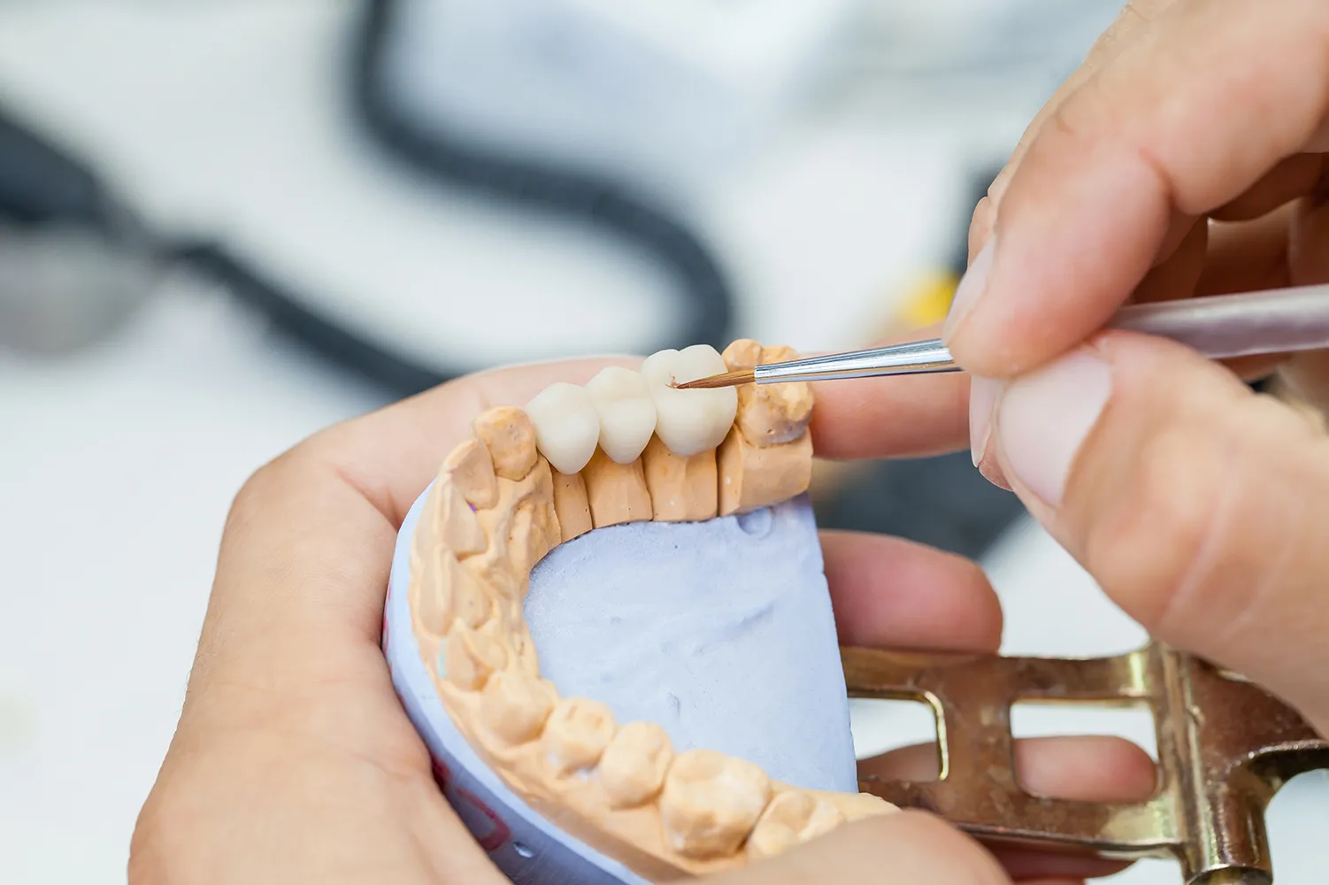 Zahnarztpraxis  Daniel Schulze  Zahntechniker arbeitet mit Pinsel und Kiefermodell